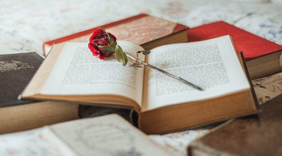 Carte deschisă cu un trandafir roșu, imagine simbolică pentru cărți romantice